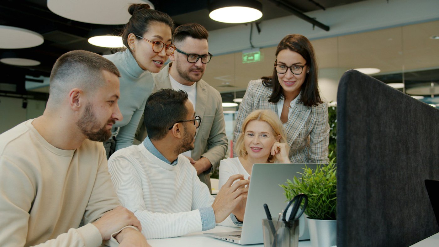 Diverse team collaborating around a laptop in a modern office